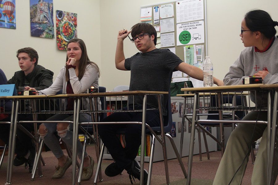 With his arms stretched, senior Tom Colling answers a question. 