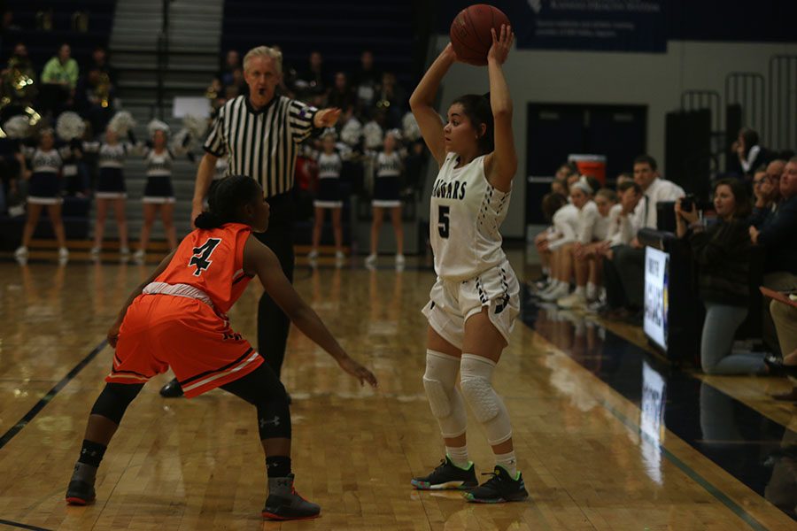 With tight defense on her, junior Presley Barton surveys the court for a pass.