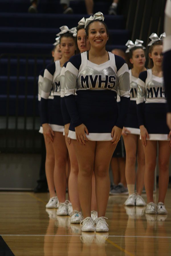 While preparing for a cheer, senior Brooke Davis smiles at a fellow cheerleader.