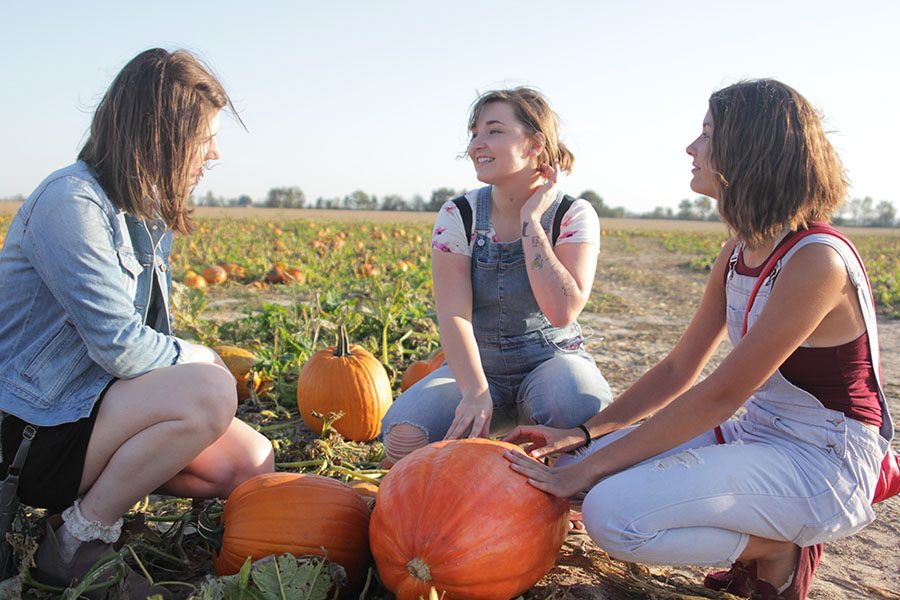 Crouching over the field, seniors Andrea Gillespie, Kiley Beran and Brynn Rittenhouse pick out pumpkins at Schaake’s Pumpkin Patch on Friday, Oct. 20.