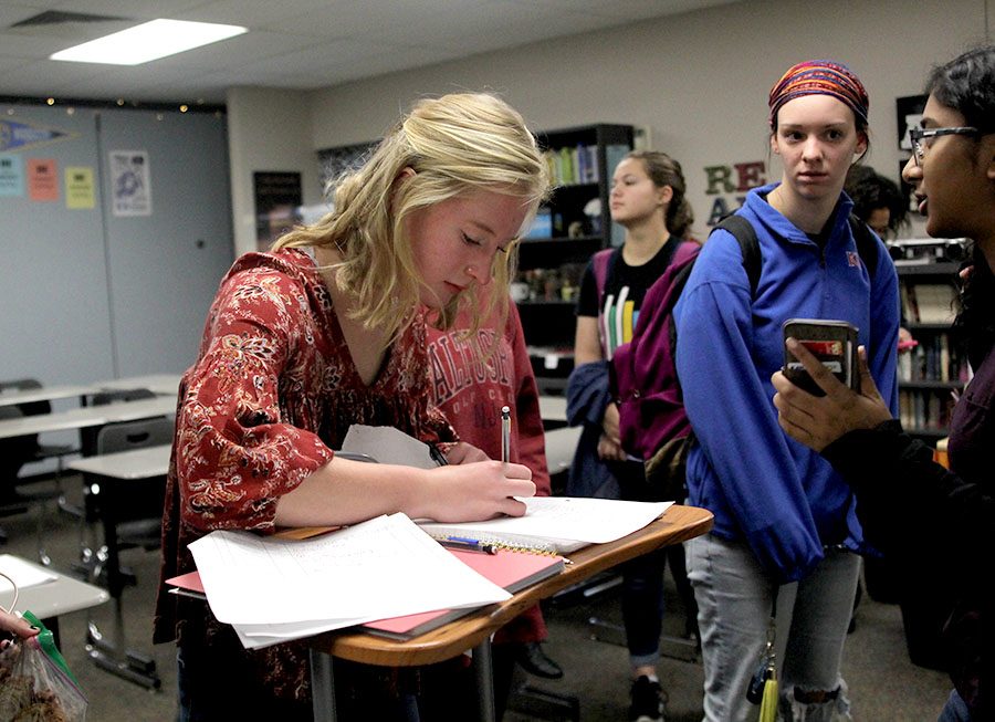 After members turned in their spooky stories for the writing contest, junior Aly Klaudt signs in at the NEHS meeting on Tuesday, Nov. 7.