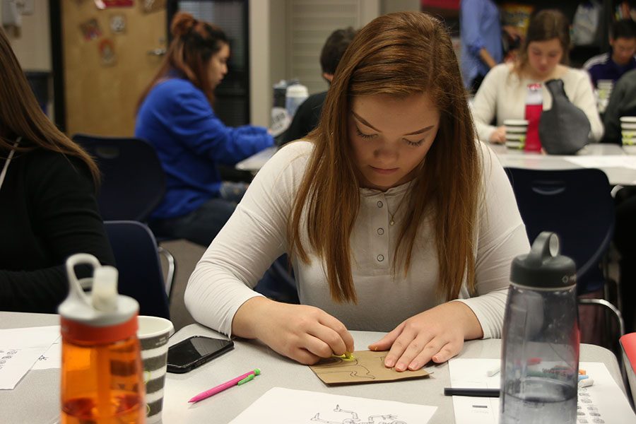 With yellow chalk in her hand, junior Lauren Harris adds color to her project on Thursday, Nov. 2.