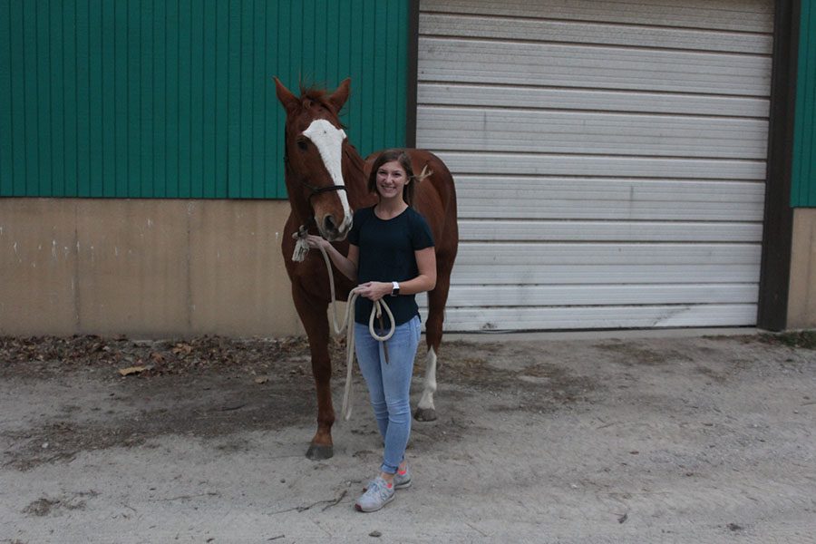Smiling next to her horse, senior Britton Nelson poses.
