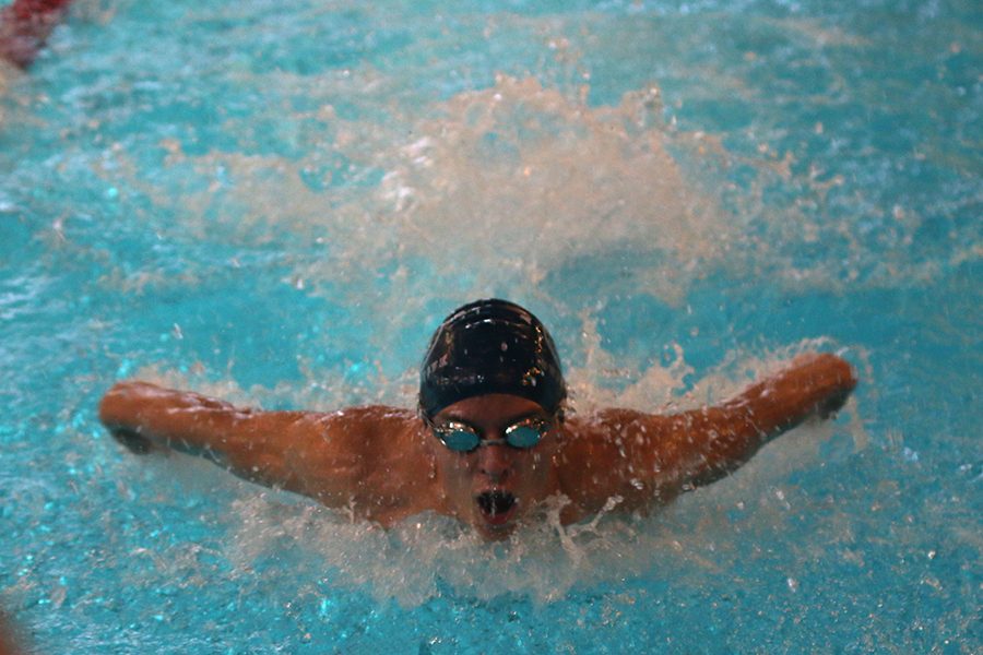 Swimming the butterfly, senior Carter Lawson takes a breath at the boys swim meet on Saturday, Dec. 2.