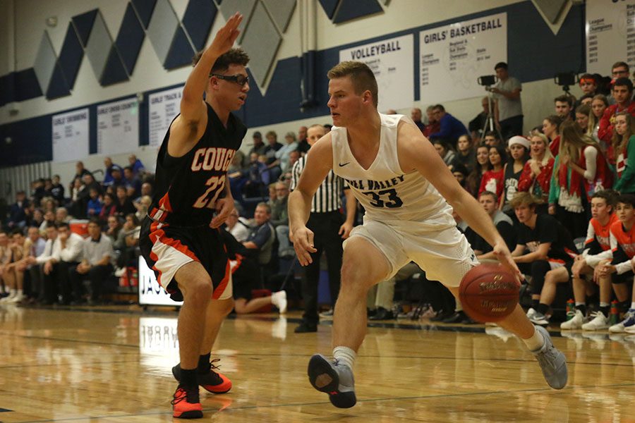 Dribbling the ball, senior Brody Flaming looks for an open path around his defender. The Jaguars were defeated by the Shawnee Mission Northwest Cougars 60-46 on Friday, Dec. 1.