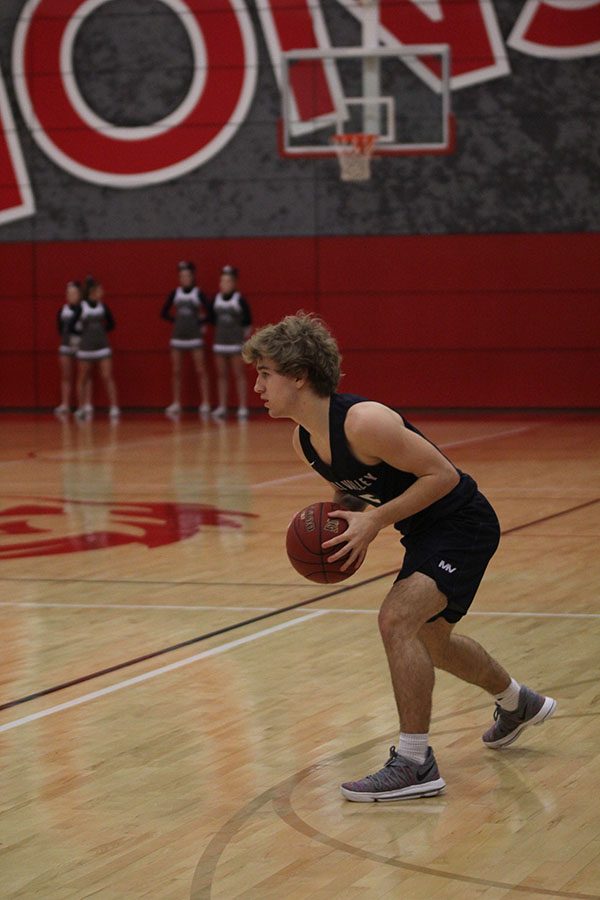 Looking for a teammate to pass to, junior Logan Talley dribbles the ball.
