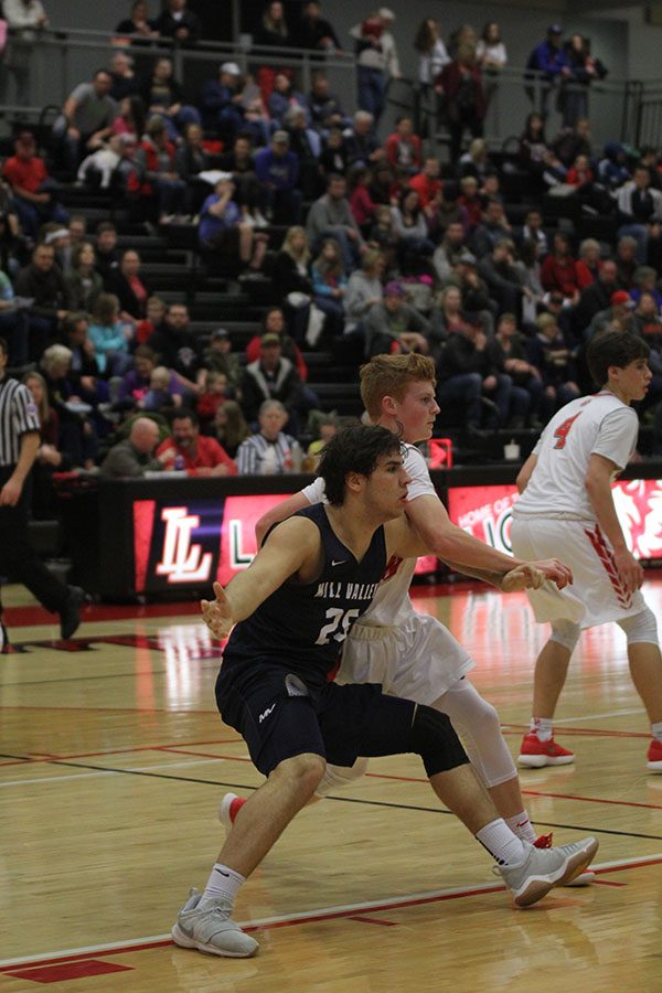 Senior Ike Valencia holds off Lansing from getting the ball.