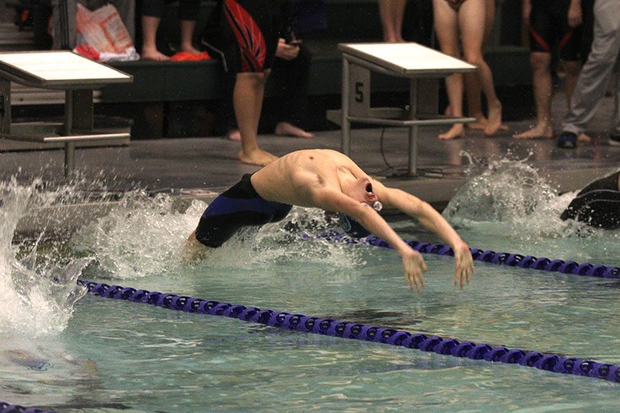At the sound of the starting buzzer, freshman Noah Collins jumps backwards to begin the 100 yard backstroke on Wednesday, Jan. 17 at Chisholm Trail Middle School.