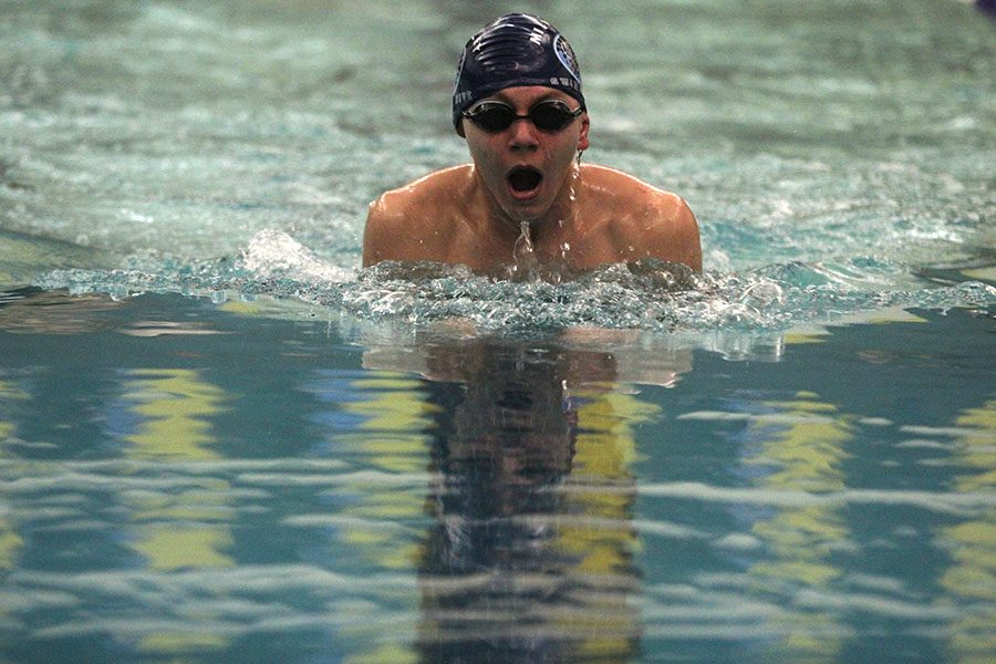 Coming up for a breath, senior Erich Schulz swims the 100 breast stroke.