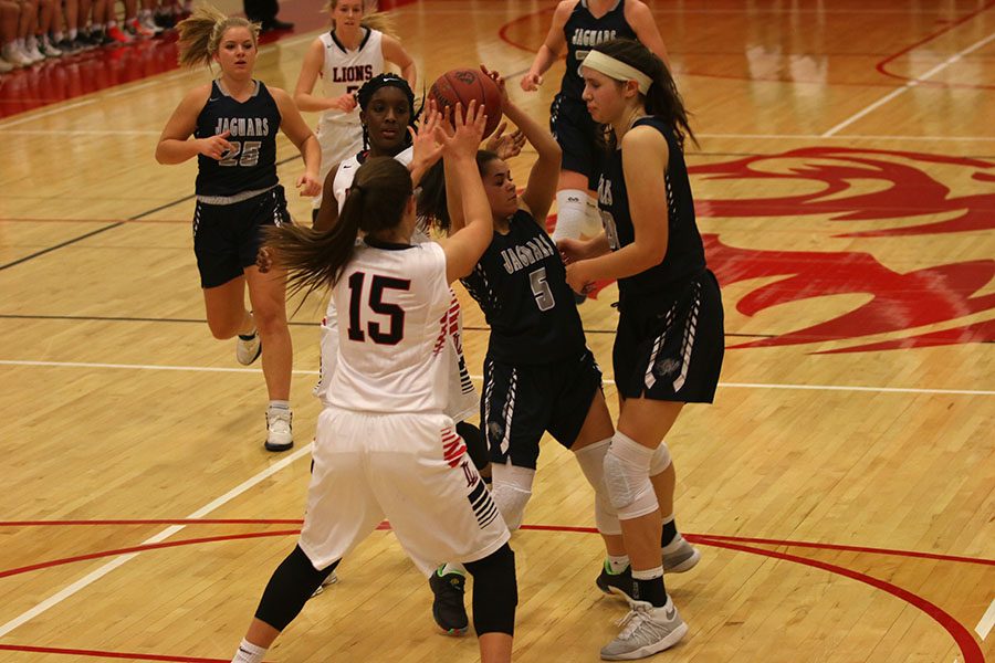 As multiple defenders try to make a steal, junior Presley Barton defends the ball at the game against the Lansing Lions on Tuesday, Jan. 16.