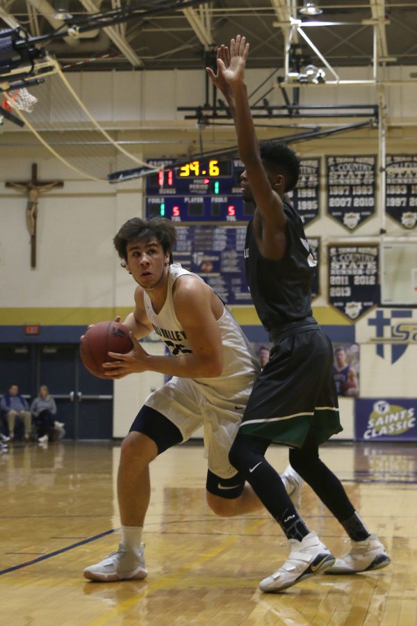 Looking towards the basket, senior Ike Valencia attempts to move around his defender.