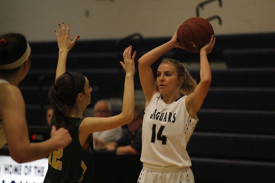 Senior Adde Hinkle grasps the ball above her head to look for an open teammate, on Monday, Jan. 22. The girls won against the Raiders, 54-40.