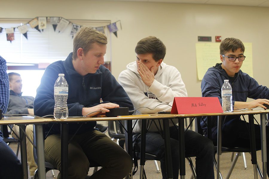 Discussing the answer to a question, senior Sam Phipps whispers to teammate senior Landon Butler during the first round of the regional tournament on Thursday, Feb. 1.