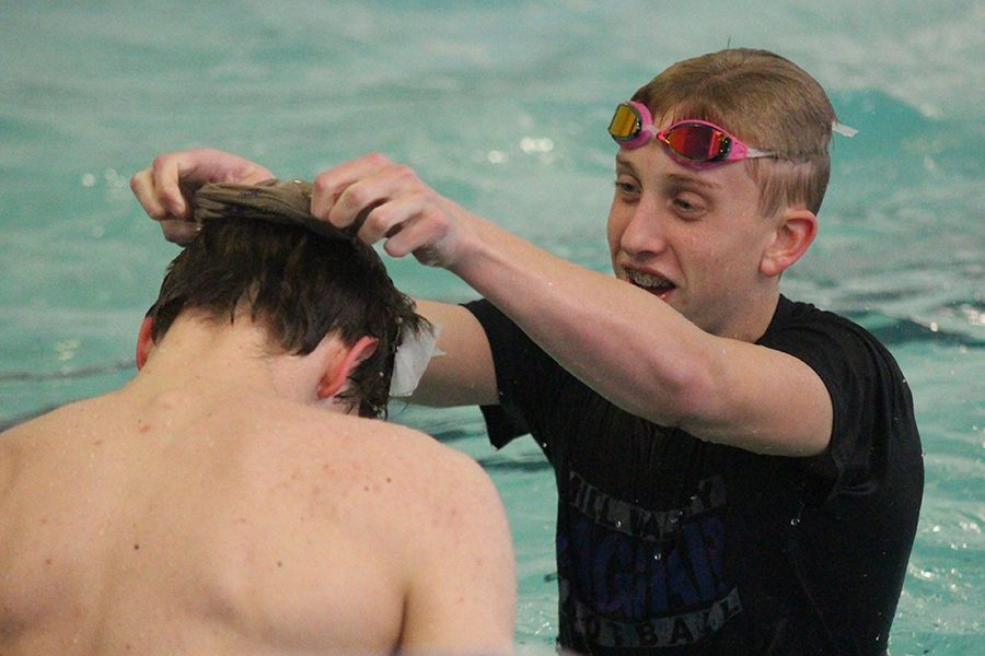 During the Swim-a-Thon, a fundraising event consisting of multiple relays and other activities, sophomore Avery Lawson pulls a sock over his teammate's head on Friday, Feb. 9 