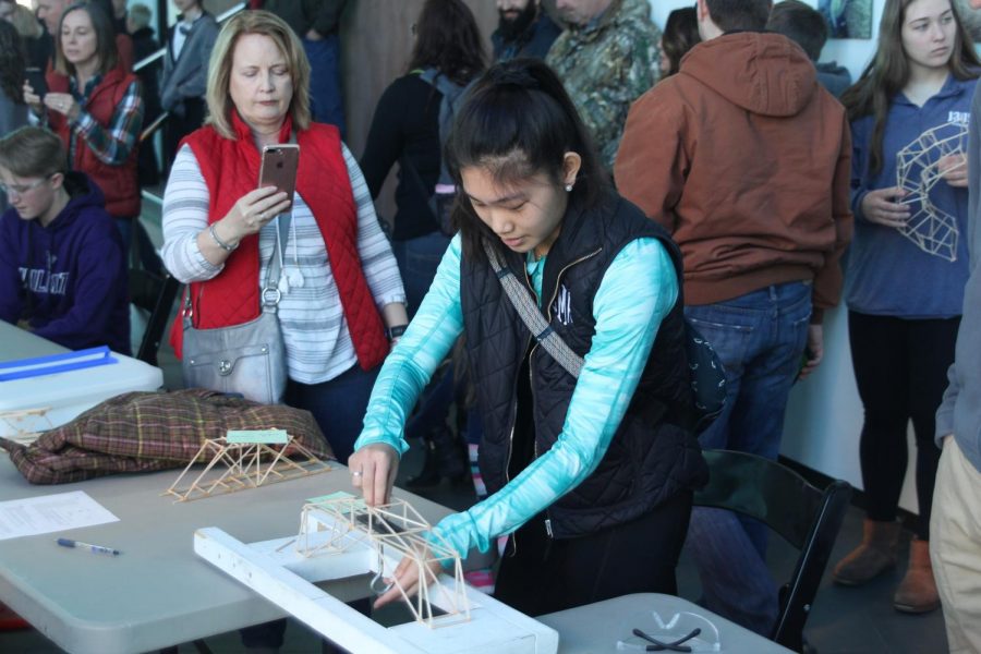 Prepping the hook to add weight, junior Libby Mullican adjusts to fit her bridge on Saturday, Feb. 3. Mill Valley along with other schools participated in the engineering bridge building competition at the Museum at Prairie Fire with the goal of testing the maximum weight against the bridge.