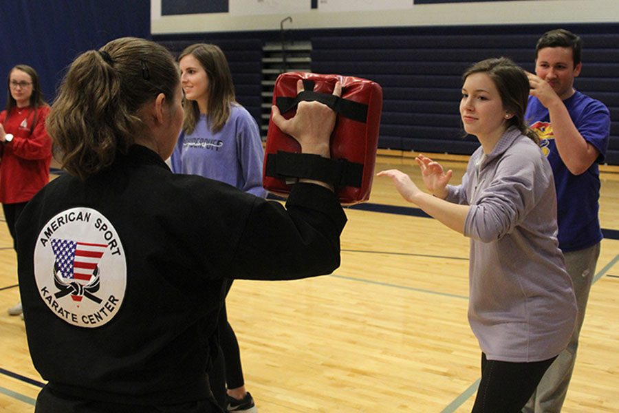 Drawing back with her right hand, junior Grace Lovett gets ready to strike at the hand target in front of her. Members of the American Sport Karate Center led a self-defense seminar on Wednesday, Jan. 31.