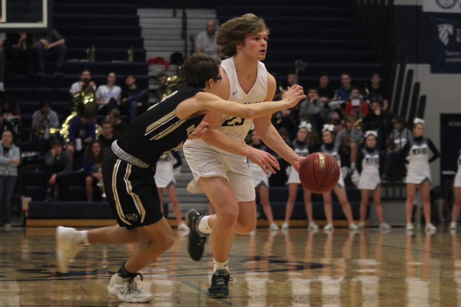 Looking for an open teammate, senior Cooper Kaifes dribbles the ball up the court.