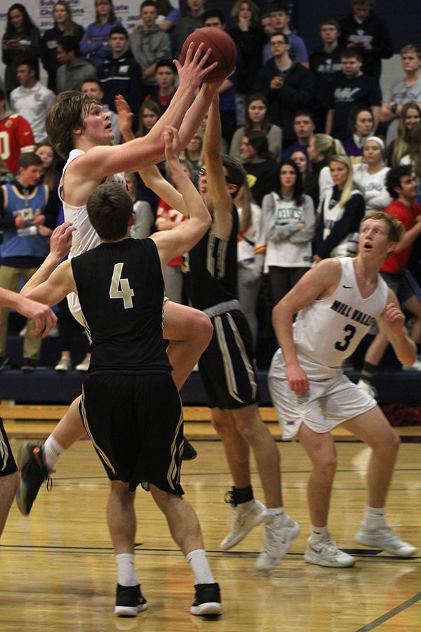Trying to avoid defenders, senior Cooper Kaifes shoots a layup.