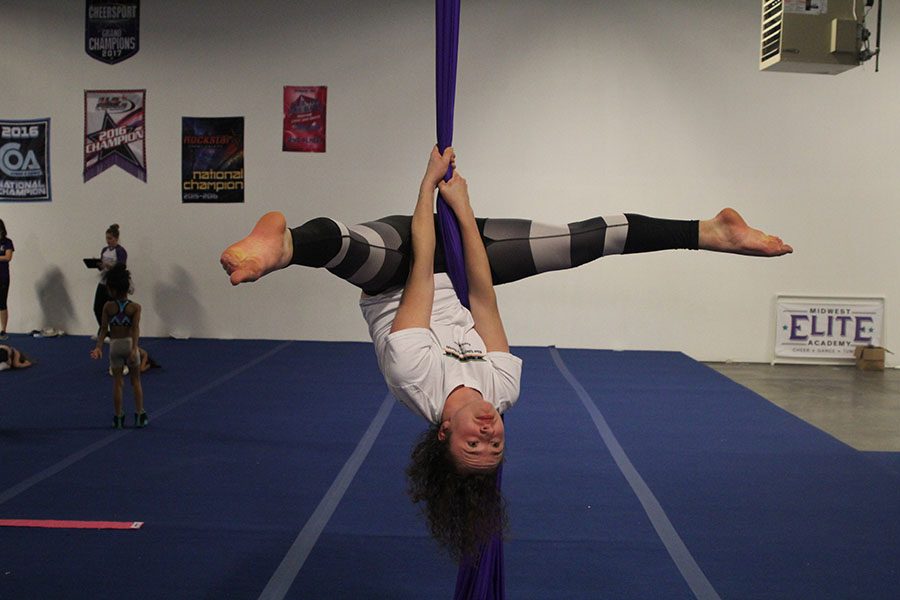 At Midwest Elite Academy, senior Parker Johnson does a straddle while suspended on aerial silks on Wednesday, Jan. 24. “It’s eerily cool because I have a fear of heights but feel safe in silks,” Johnson said.