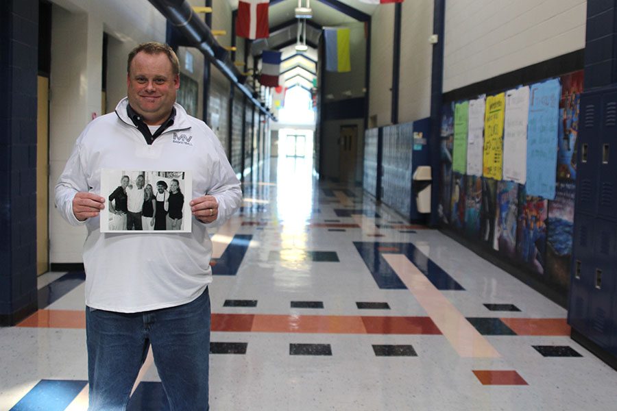 Holding up a photo of former coworkers from his 18 years of experience in the restaurant industry, math teacher Kevin Mosher stands in the main hallway. Mosher worked as a waiter, manager and executive chef before becoming a teacher in 2010.