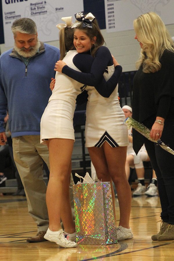 Senior Bella Knight hugs a fellow cheerleader on senior night.