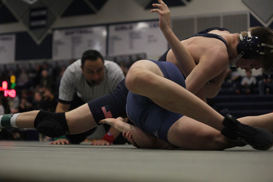 As the ref watches for a pin, senior Jarrett Bendure pushes his opponent towards the mat.