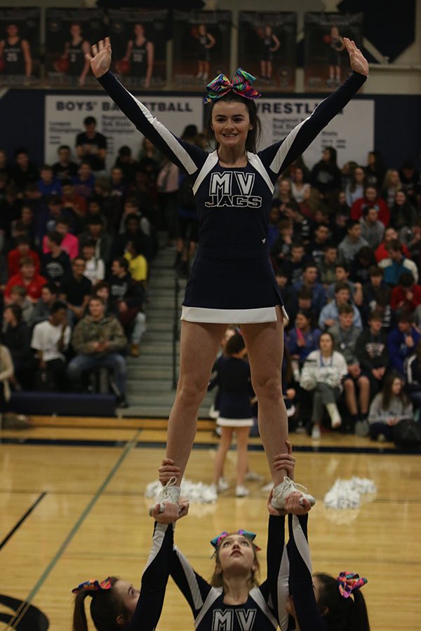 While being held in the air, senior Heather Winne waves to the crowd.
