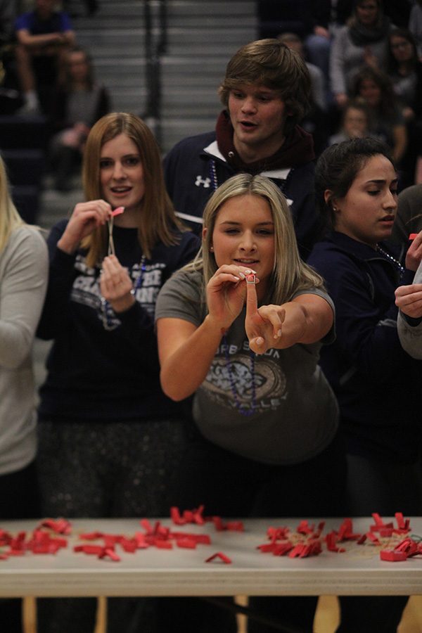 Senior Lucy Holland shoots a rubber band at plastic cups during the candidate game on Friday Feb. 9.