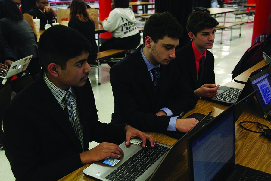 Preparing to compete in public forum debate on Friday, Feb. 23, freshman Manoj Turaga, senior Michael Sandri and freshman Luke Capri discuss speeches and notes at Shawnee Mission North.