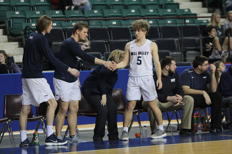 After coming off the court, junior Logan Talley high-fives seniors Brody Flaming and Ben Weigel. 