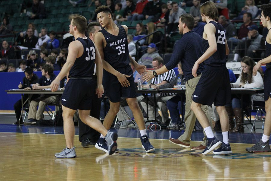 During a timeout, freshman Keeshawn Mason high-fives assistant coach Zach McFall.