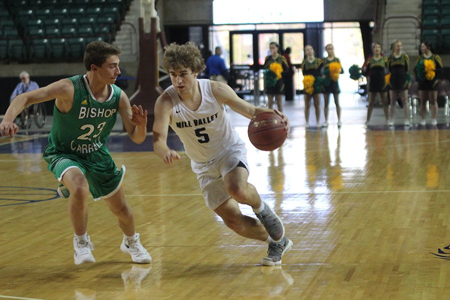 Dribbling past his opponent, junior Logan Talley runs down the court.