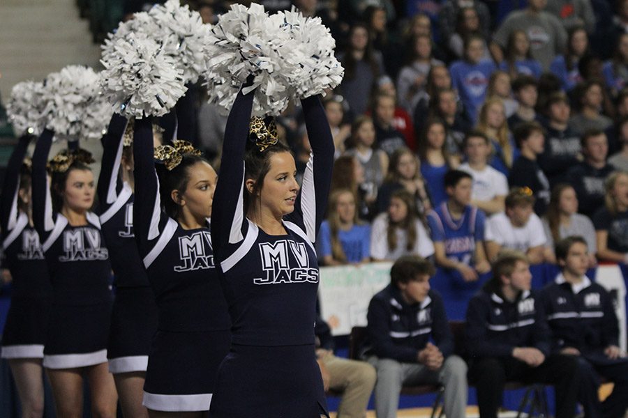 While a player shoots a free throw, senior Alexa Horton cheers on the boys basketball team.