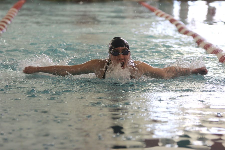 Reaching out of the water, freshman Grace McLeod swims the 100-yard butterfly.