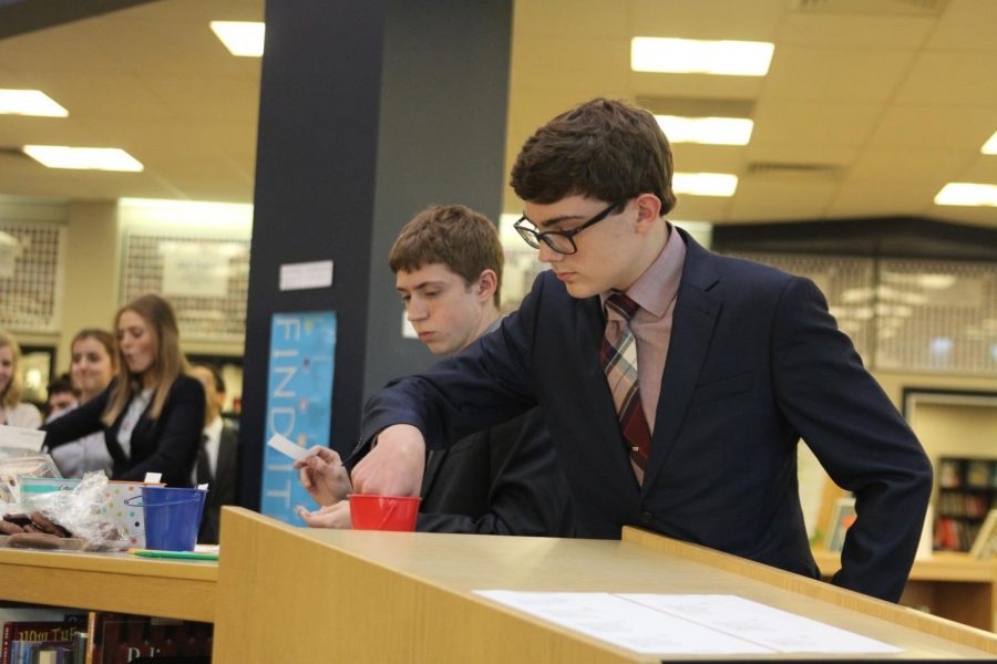 Freshman Zachary Botkin draws a slip of paper from the red cup which will tell him the topic of the speech he will soon write within the next half hour.