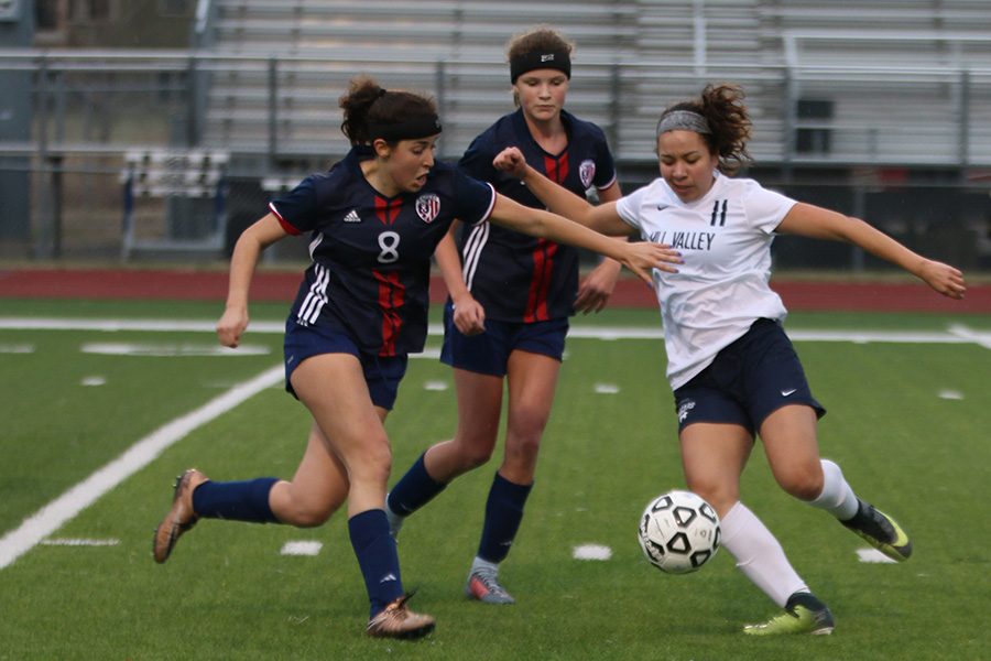 As Olathe North defenders close in, sophomore Cristina Talavera focuses on the ball during the game on Wednesday, March 28. 