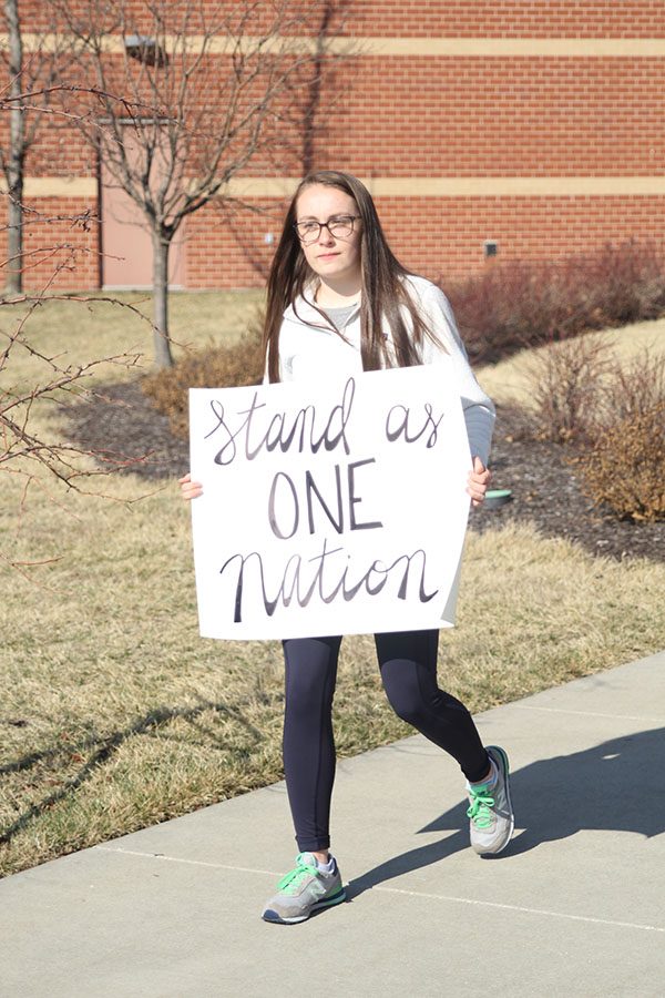 Junior Delaney Kemp holds her sign as she goes to take a seat before the walkout.