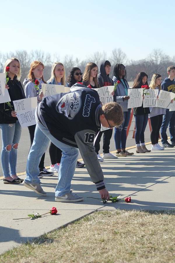 Dropping a rose in remembrance, senior Carter Lawson leans over.