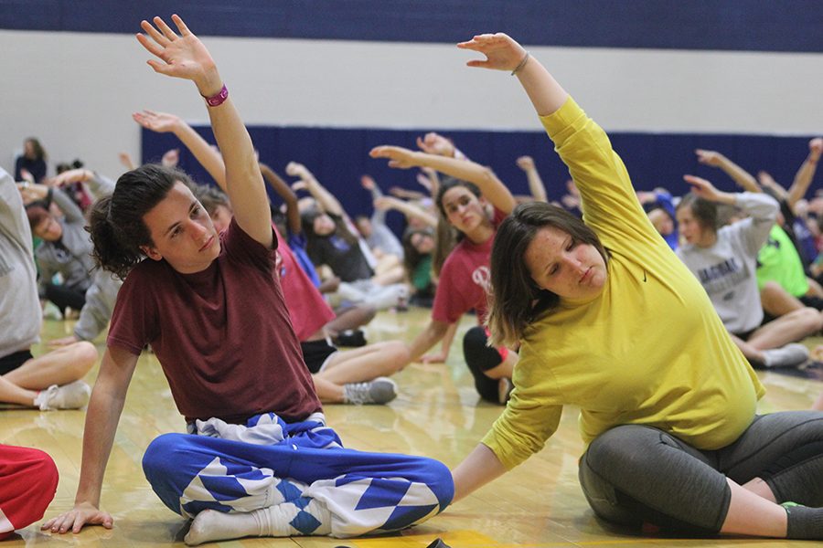 Senior Cody Robertson and junior Avery Sheltra stretch during sunrise yoga.
