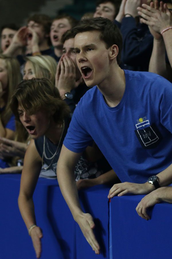 Smacking his hand against the wall to make noise, senior Artur Chlopecki cheers the team on.