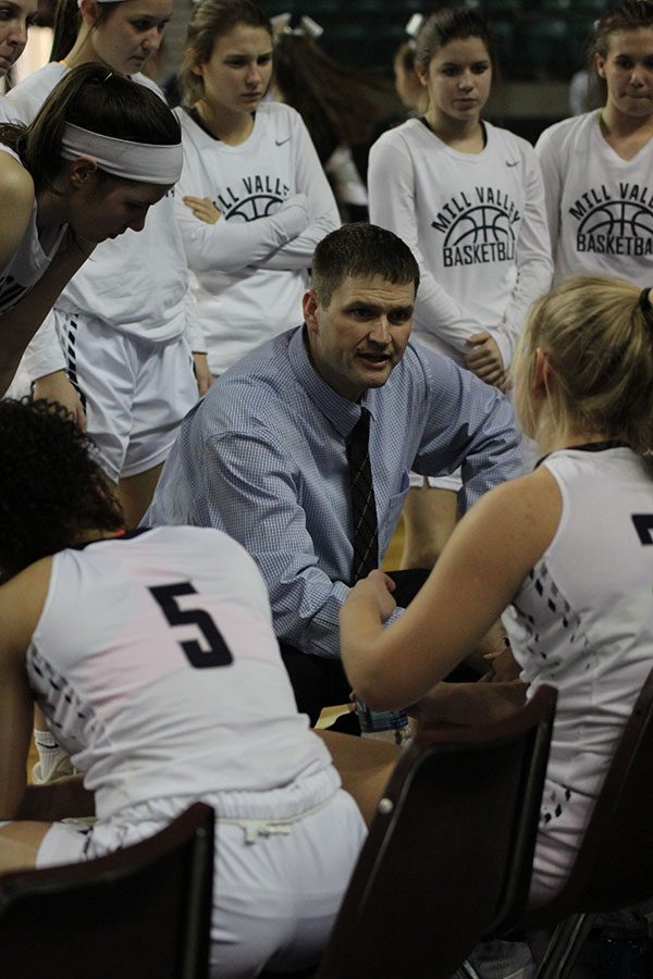 During a timeout, head coach Drew Walters kneels to talk to the team.