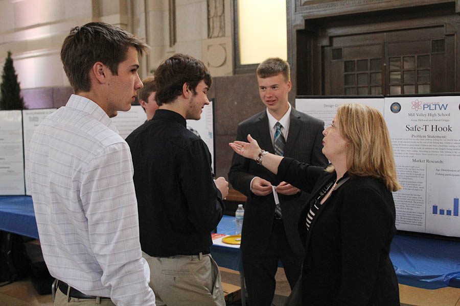Engineering teacher Gayle Kebodeaux talks with seniors Kyle Bonsetter, Jonas McLeod and Jarod Griggs as they set up their presentations. 