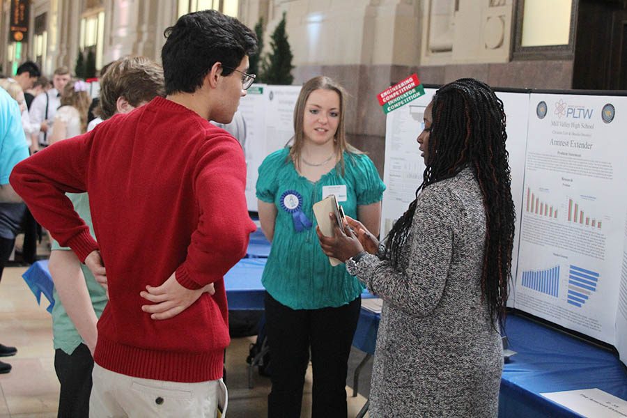 Seniors Desola Ominyi and Christine Lust explain their project, a device that would divide the space between airplane seats, to juniors Matthew Richle and Andrew Thomas.