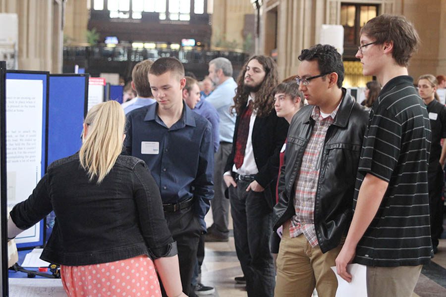 Juniors Will Hecht and Andrew Vargas listen to students from a different school as they share their project.