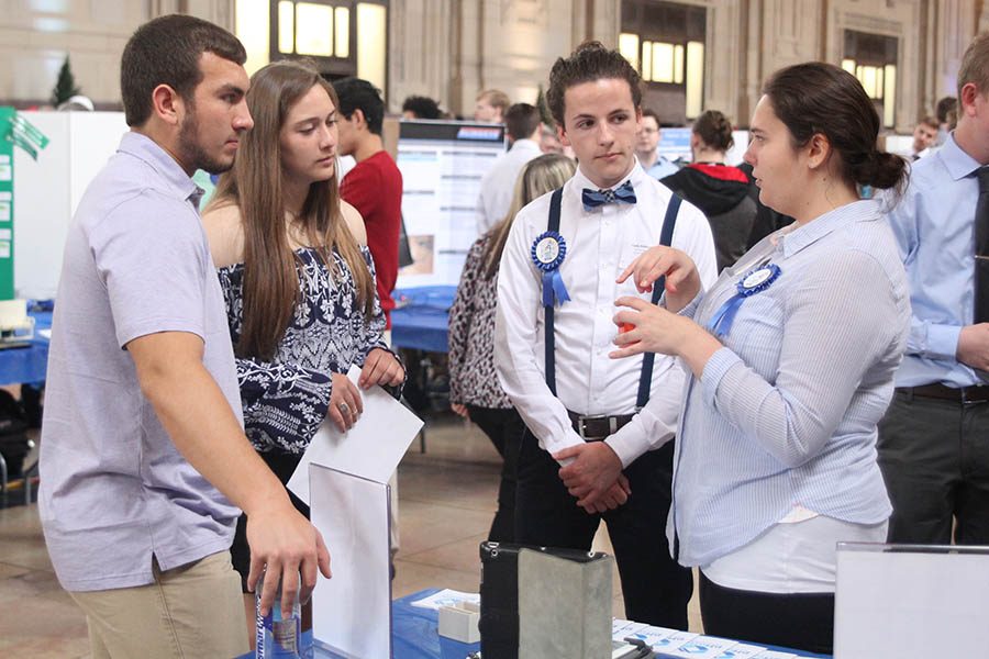 Senior Amanda Hertel explains her project, in collaboration with seniors Cody Robertson, Landon Butler and Ethan Jacobson, to juniors McKenna Elliott and Christian Roth at the engineering senior showcase on Wednesday, April 25.