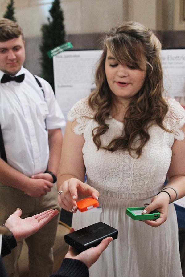 To highlight the weight difference of portable batteries, senior Maggie Miller talks with a viewer. 