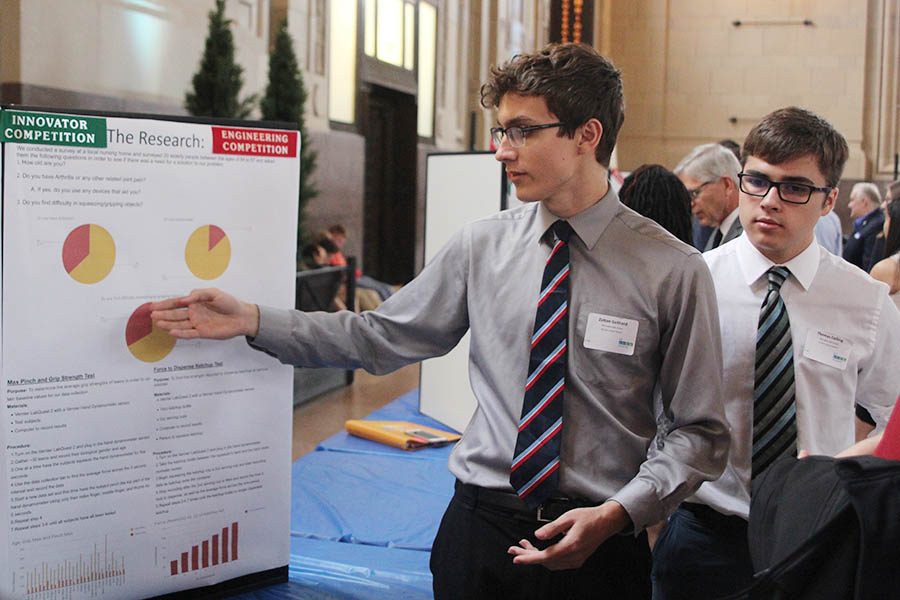 To further explain his groups project, senior Zoltan Gothard gestures to the pie graphs on the board of his and senior Tom Collings presentation. 