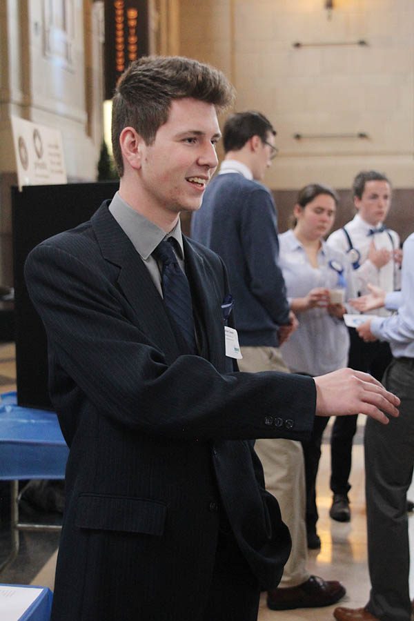 Senior Nate Cowan talks with a spectator as he explains his groups project. 