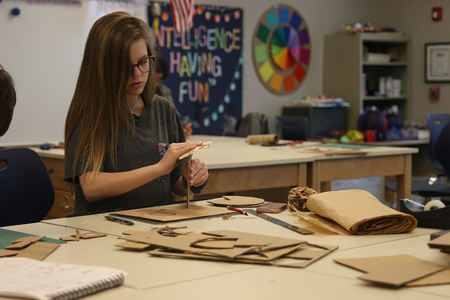 Focused on building her sculpture, freshman Keirstin Swanson sands down pieces of cardboard to create the right shape on Friday, April 13. 
