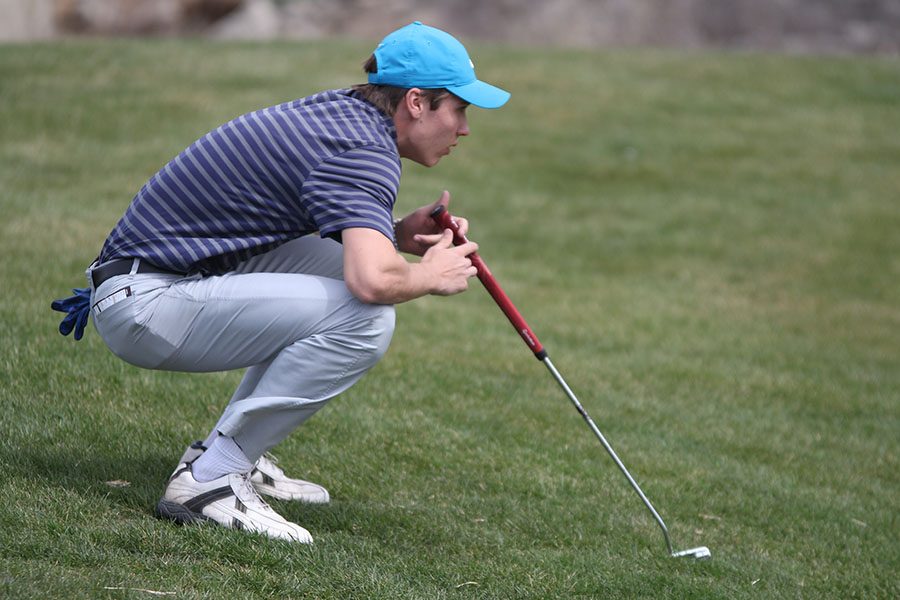 Concentrating on the ball, senior Kyle Bonnstetter lines up his putt.			